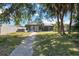Spacious backyard featuring a screened lanai, mature trees, and a concrete walkway at 108 Martin Ne Dr, Port Charlotte, FL 33952