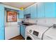 Functional laundry room with modern appliances, a deep sink, and striking blue cabinetry, creating a stylish and efficient space at 11 1St E St, Nokomis, FL 34275