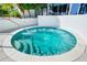 Inviting turquoise in-ground hot tub with metal assist bar and limestone tile surround at 1155 N Gulfstream Ave # 508, Sarasota, FL 34236
