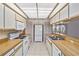 Well-lit kitchen featuring white appliances and cabinets, complemented by wood countertops and checkered wallpaper accents at 125 Golf Club Ln, Venice, FL 34293