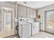 Bright laundry room featuring a washer, dryer, storage cabinets, and light wood-look vinyl floors at 125 Golf Club Ln, Venice, FL 34293