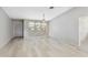 Open-concept living area with light wood-look floors, a ceiling fan, and natural light from three large windows at 125 Golf Club Ln, Venice, FL 34293