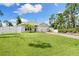 Inviting single-story home with a lush green lawn, palm trees, a two-car garage, and a vinyl privacy fence at 13339 Flaherty Ave, Port Charlotte, FL 33981