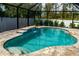 Beautiful screened-in pool area with a waterfall feature, stone pavers and lush landscaping at 13339 Flaherty Ave, Port Charlotte, FL 33981