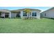 Expansive backyard with lush green lawn and modern home design featuring large windows and a palm tree at 17916 Palmiste Dr, Bradenton, FL 34202