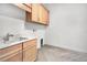 Bright laundry room with wood cabinets, a utility sink, and herringbone flooring at 17916 Palmiste Dr, Bradenton, FL 34202