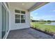 Covered patio with brick flooring offering scenic views of the lake and manicured lawn, perfect for relaxation at 17916 Palmiste Dr, Bradenton, FL 34202