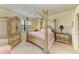 Ornate bedroom boasting a four-poster bed, neutral walls, and large windows overlooking the yard at 19889 Benissimo Dr, Venice, FL 34293
