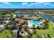Aerial view showcasing a resort-style pool, tennis courts, and clubhouse amidst tropical landscaping at 19889 Benissimo Dr, Venice, FL 34293