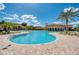 Large lagoon style pool with beach style entry, surrounded by lounge chairs, tables, umbrellas, and lush landscaping at 19889 Benissimo Dr, Venice, FL 34293