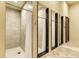 Community showers with tile walls and floors, privacy curtains, and black-framed mirrors at 19889 Benissimo Dr, Venice, FL 34293