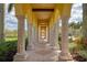 Covered outdoor walkway featuring stone columns and arched openings, providing a scenic view at 19889 Benissimo Dr, Venice, FL 34293