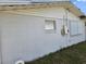 View of the exterior wall with a window, and a metal panel and showing peeling paint and damage at 2061 Georgia Ave, Englewood, FL 34224