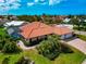 A beautiful home showcasing its terracotta roof, screened-in pool, and well-manicured lawn in a tropical setting at 284 Lookout Point Dr, Osprey, FL 34229