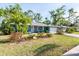 Quaint blue home with a lovely front yard featuring mature palm trees and tidy landscaping at 2933 Mayflower St, Sarasota, FL 34231