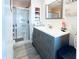 Bathroom features a gray vanity with a walk-in shower, a framed mirror, and decorative accents at 3414 Spanish Oak Ter, Sarasota, FL 34237