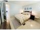 Cozy bedroom showcasing beach-themed wall art above a queen bed with nightstands and a vintage metal chair at 3414 Spanish Oak Ter, Sarasota, FL 34237