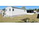 Exterior view of home's white siding, green lawn, with modern AC unit, and a covered porch at 3414 Spanish Oak Ter, Sarasota, FL 34237