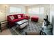 Cozy living room features a plush red sofa, decorative rug, and sunlit bay windows at 3414 Spanish Oak Ter, Sarasota, FL 34237
