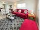 Comfortable living room with a vibrant red sofa, decorative accents, and a view into the dining area at 3414 Spanish Oak Ter, Sarasota, FL 34237
