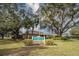 Pinebrook Clubhouse entrance with lush landscaping, mature trees, American flag and welcoming signage at 3780 Pinebrook Cir # 102, Bradenton, FL 34209