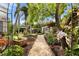 Lush backyard with gravel path, a variety of trees and flowers, and a potting shed at 4109 Riverview Blvd, Bradenton, FL 34209