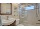 Bathroom with tiled shower and glass doors, updated sink with dark wood cabinet, and decorative shelving at 4181 Brittany Ln # 25, Sarasota, FL 34233