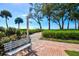 Beautiful brick and sand beach path with lush greenery and a bench overlooking the ocean at 5055 Gulf Of Mexico Dr # 115, Longboat Key, FL 34228