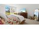 Comfortable bedroom with large window, TV, dresser and mirror with a colorful bedspread at 5055 Gulf Of Mexico Dr # 115, Longboat Key, FL 34228
