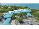 Aerial view capturing the condo community with vibrant blue roofs, ample parking, and scenic ocean view in the distance at 515 Spring Lakes Blvd # 515, Bradenton, FL 34210