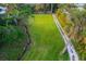 Aerial view of a large grassy property lot, featuring a stream and winding drive at 5247 Carmilfra Dr, Sarasota, FL 34231