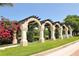 Beautiful arched pergola covered with bougainvillea separates walkway from the street with lush green bushes and manicured lawn at 5270 Far Oak Cir, Sarasota, FL 34238