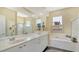 Well-lit bathroom featuring double sinks, separate shower, and bathtub, with neutral tile flooring at 5270 Far Oak Cir, Sarasota, FL 34238