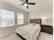 Well-lit bedroom with a ceiling fan, two windows, and plush carpeting at 5336 Grove Mill Loop, Lakewood Ranch, FL 34211