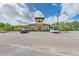 Attractive community clubhouse with manicured landscaping, parking, and a decorative tower under a partly cloudy sky at 5336 Grove Mill Loop, Lakewood Ranch, FL 34211