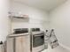 Modern laundry room with stainless steel washer, dryer, and storage shelves at 5336 Grove Mill Loop, Lakewood Ranch, FL 34211