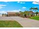 Charming single-story home with lush tropical landscaping, expansive driveway, and a welcoming two-car garage at 5563 America Dr, Sarasota, FL 34231