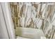 Bathroom showing a bathtub with white and brown marble-like wall tile at 5963 Midnight Pass Rd # 355, Sarasota, FL 34242