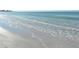 A calming shot of waves gently lapping onto the sandy beach under a sunny sky at 5963 Midnight Pass Rd # 355, Sarasota, FL 34242