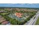Aerial view of a community clubhouse featuring tennis courts, swimming pool and a large parking area at 6324 41St E Ct, Sarasota, FL 34243