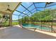 Screened-in pool area with a splash pool and waterfall feature, surrounded by lush greenery and a safety fence at 6324 41St E Ct, Sarasota, FL 34243