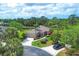 Aerial view of a home with lush landscaping, circular driveway, and a peaceful pond backdrop at 7710 Seven Oaks Dr, Bradenton, FL 34201