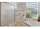 Bright bathroom featuring a walk-in shower, soaking tub and a glass block window at 7816 Ashley Cir, University Park, FL 34201