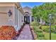 Inviting home entrance with brick walkway, manicured gardens, and a stylish front door at 7816 Ashley Cir, University Park, FL 34201
