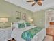 Bright main bedroom with light green walls, white furniture, and tropical accents at 7816 Ashley Cir, University Park, FL 34201
