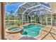 Screened-in pool and spa area with lush surroundings and a serene lake view at 7816 Ashley Cir, University Park, FL 34201