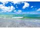 Beautiful beach view of ocean waves, clear water, and boats sailing in the distance under a sunny sky at 800 S Blvd Of The Presidents # 3, Sarasota, FL 34236