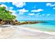 Picturesque beach featuring white sand, clear turquoise water, and natural rock barriers with blue skies overhead at 800 S Blvd Of The Presidents # 3, Sarasota, FL 34236
