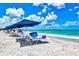 Peaceful beachfront scene featuring turquoise waters and beachgoers relaxing under blue umbrellas on a sunny day at 800 S Blvd Of The Presidents # 3, Sarasota, FL 34236