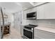 Bright kitchen featuring stainless steel oven and microwave with white cabinets and dining area nearby at 800 S Blvd Of The Presidents # 3, Sarasota, FL 34236